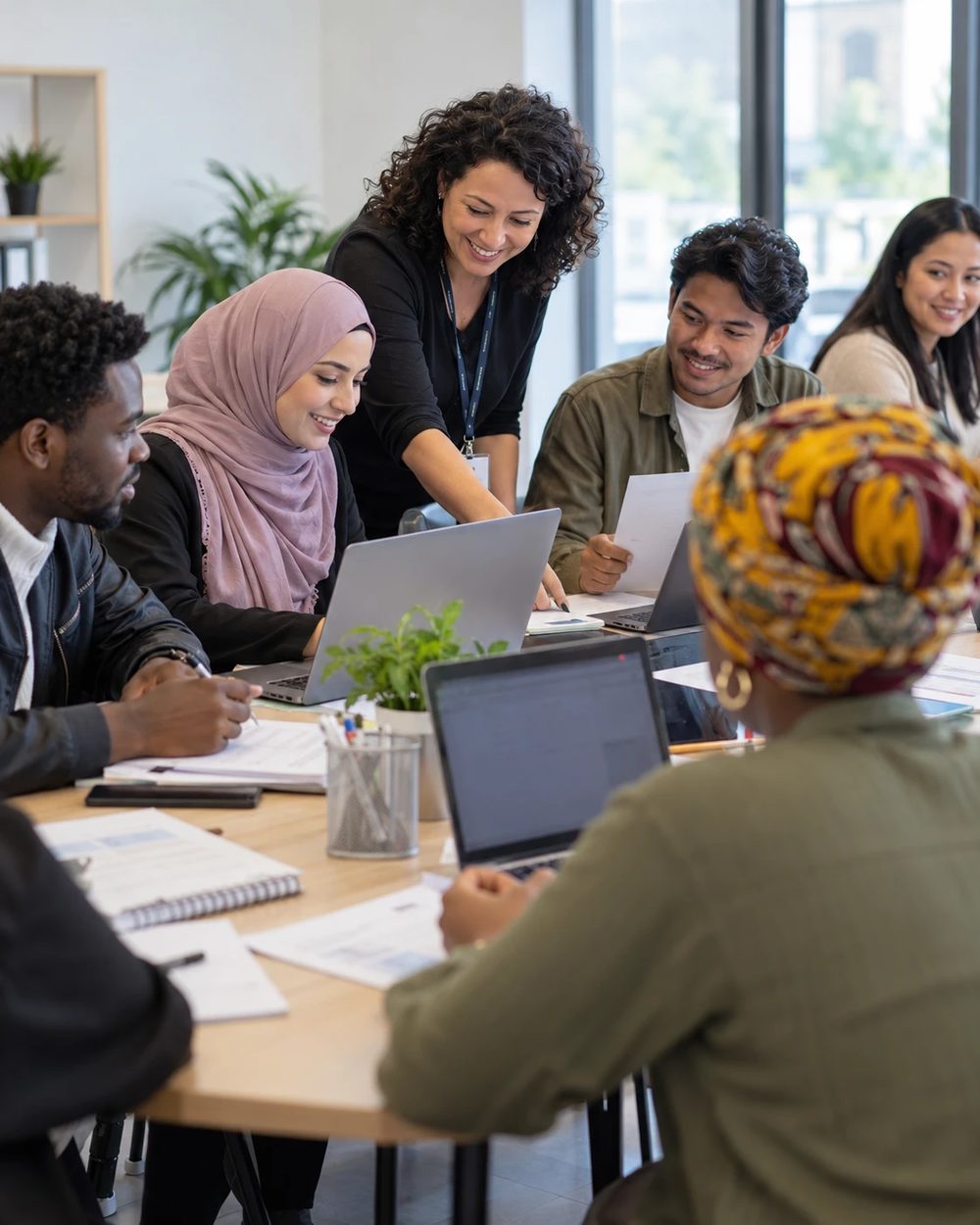 A facilitator helping participants working on laptops in a training room