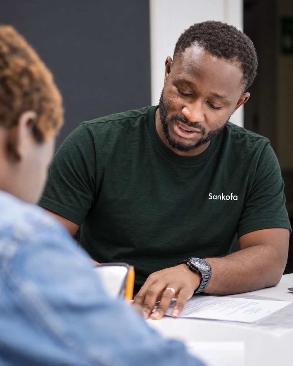 A Sankofa facilitator reviewing a printed resume with a participant